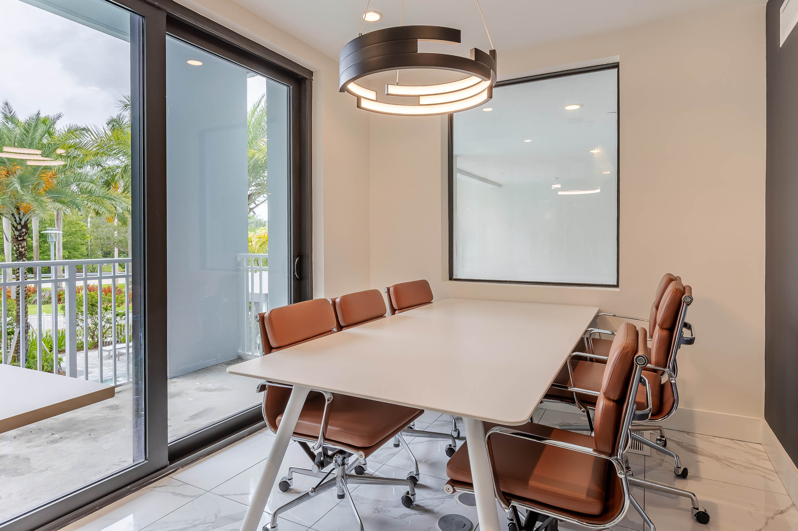 AMLI Park West apartment private office with rectangular conference table and desk chairs and chandelier with patio view