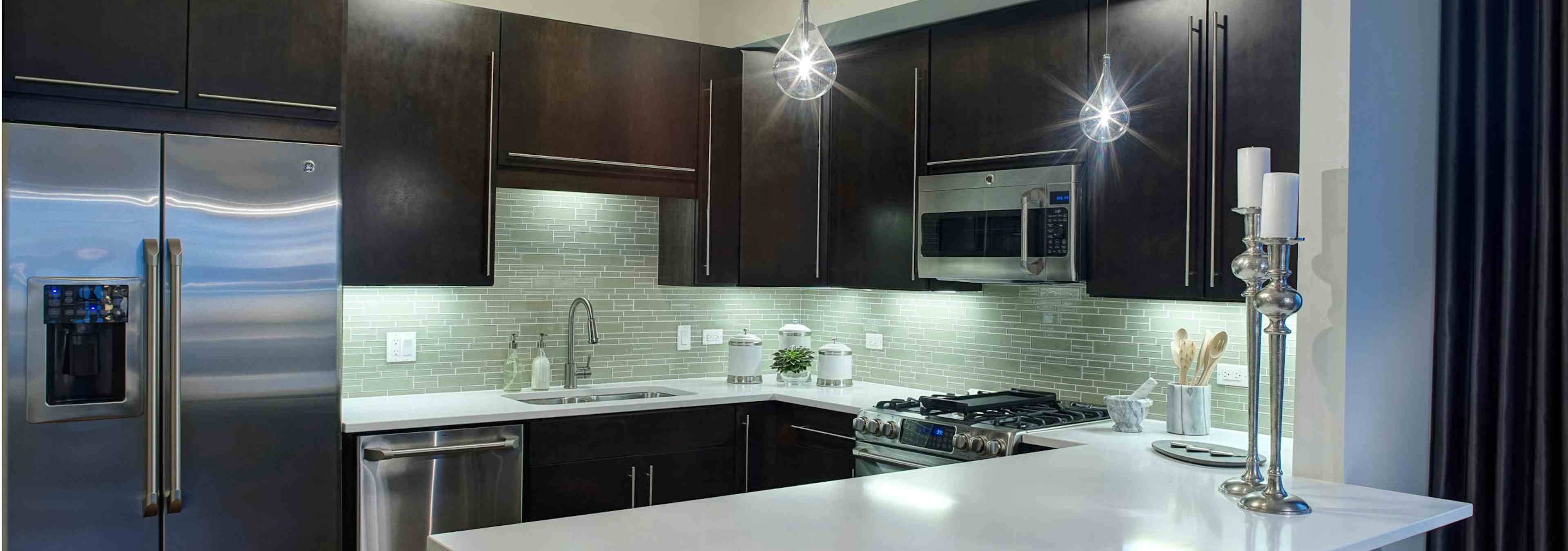AMLI River North penthouse kitchen with two candle sticks on a quartz counter and dark wood cabinets visible in the back