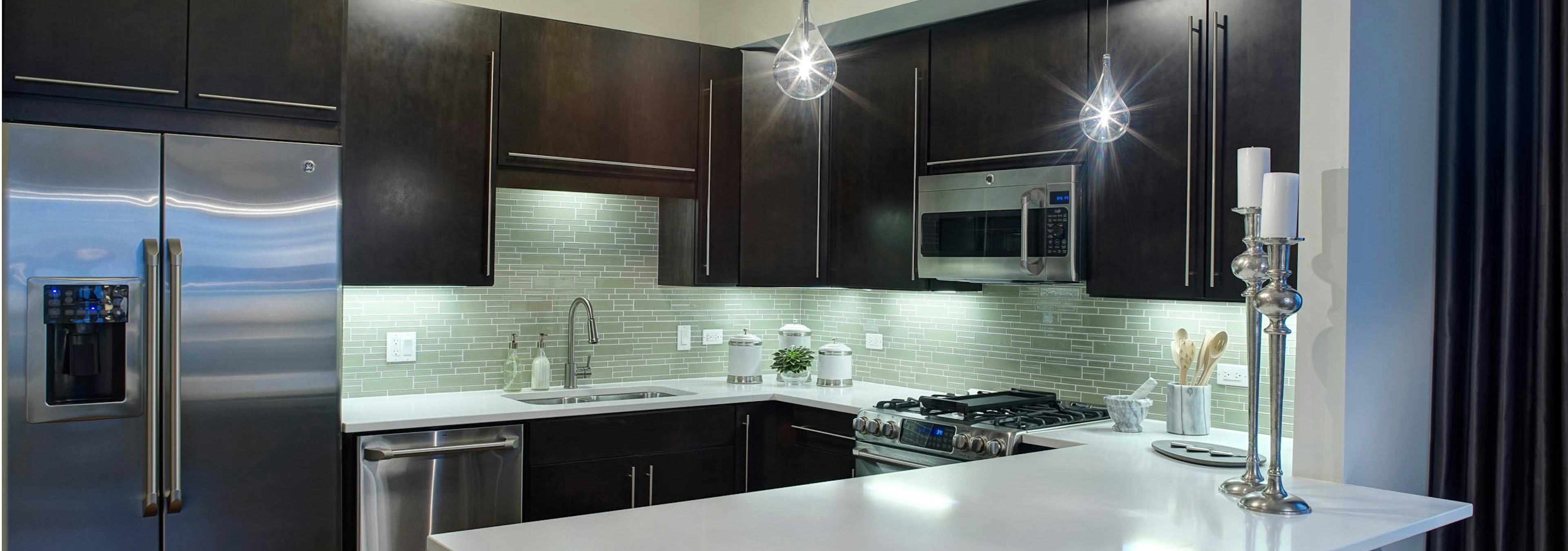 AMLI River North penthouse kitchen with two candle sticks on a quartz counter and dark wood cabinets visible in the back