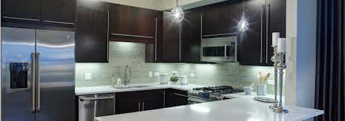 AMLI River North penthouse kitchen with two candle sticks on a quartz counter and dark wood cabinets visible in the back