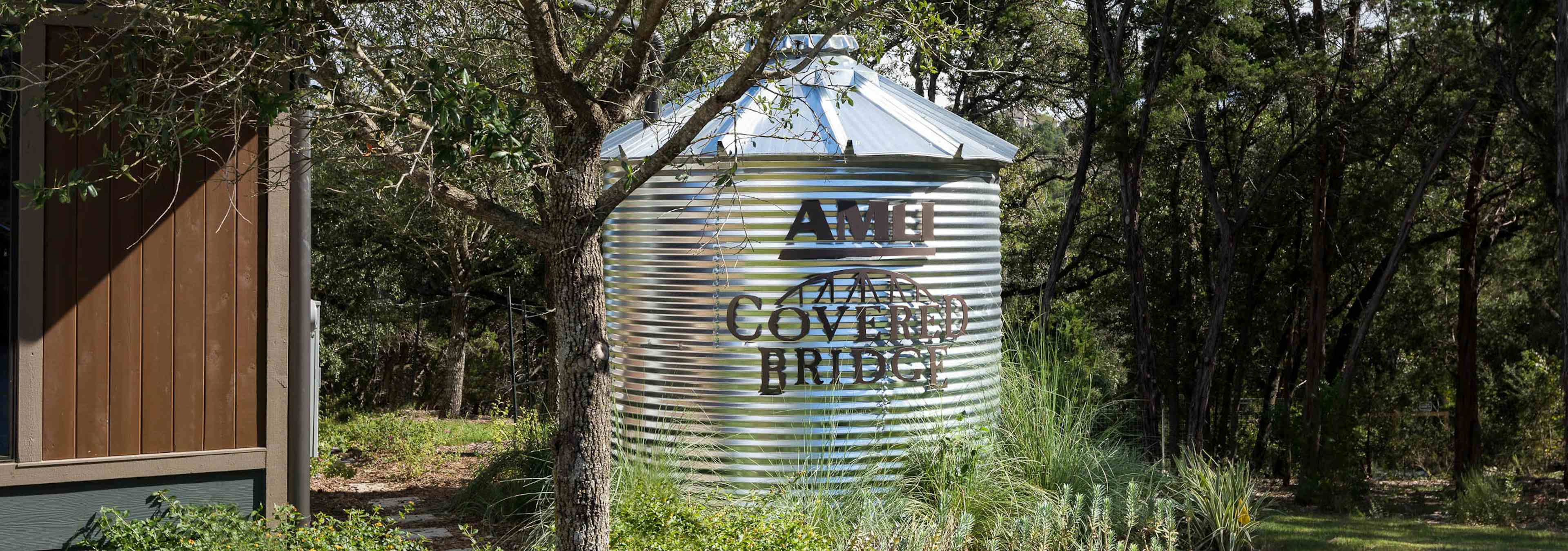 AMLI Covered Bridge apartment community sign on a water tank nestled between tall green trees