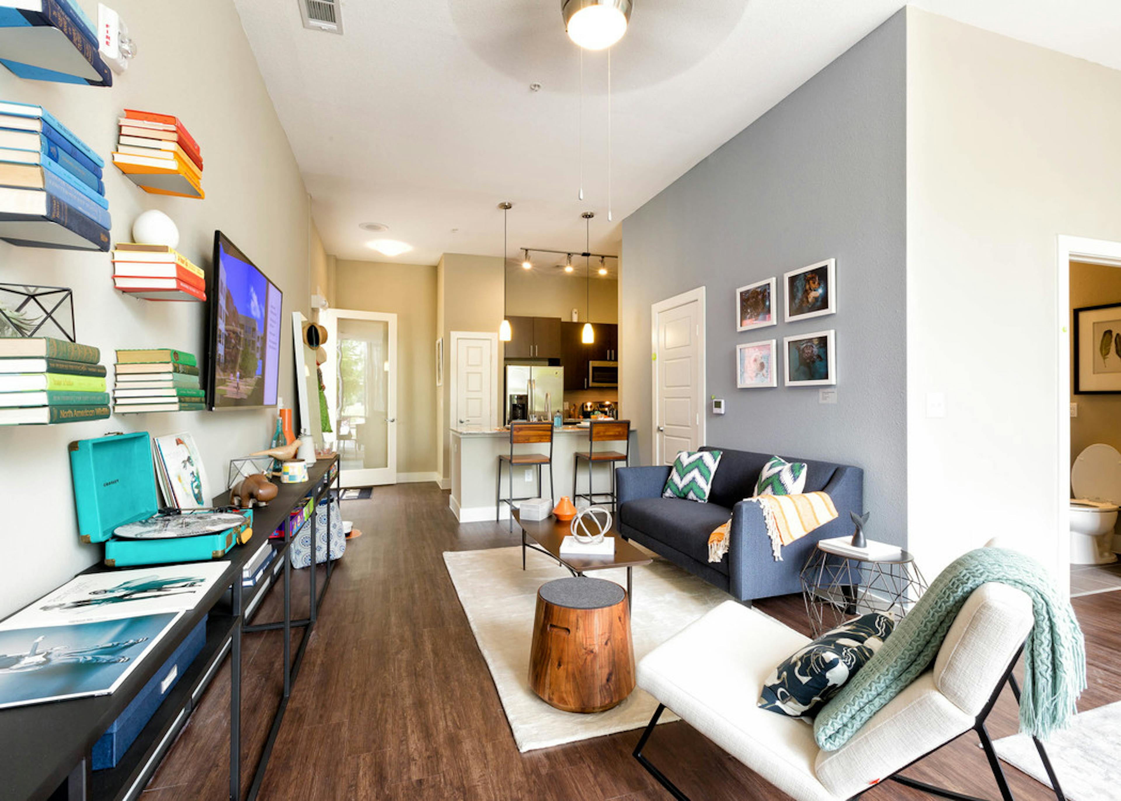 Interior view of AMLI at Mueller living room with dark wood floors and a grey couch on a white rug with colorful decor 