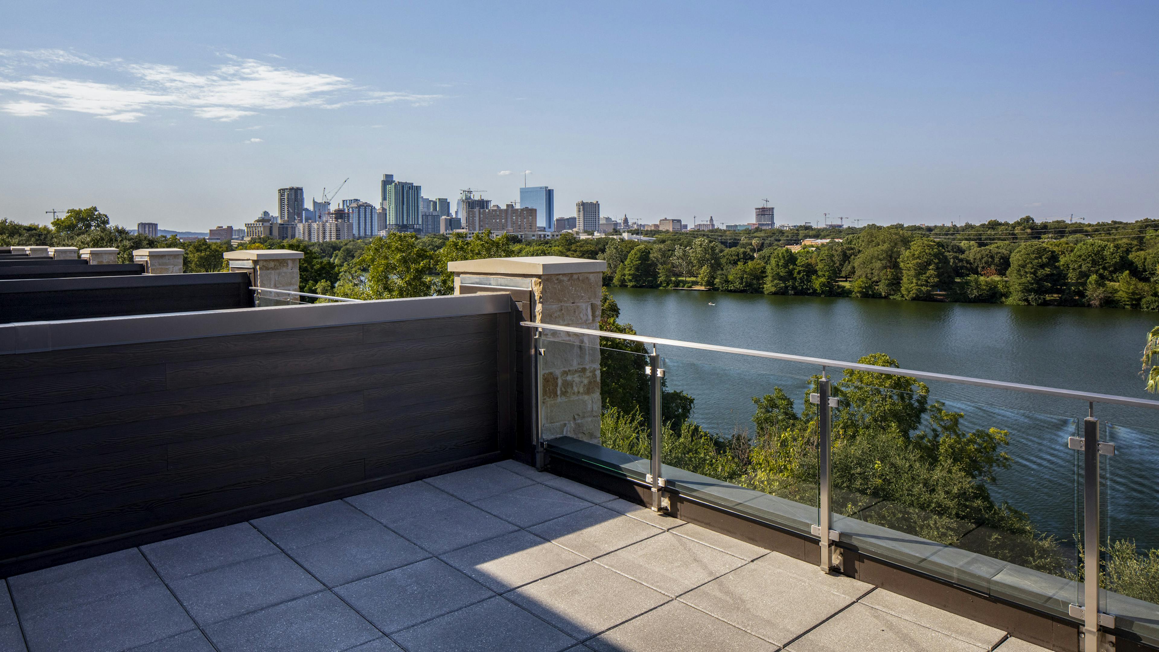 Daytime view of tree lined lake and downtown Austin skyline from 4th floor deck of AMLI South Shore lakefront apartment home