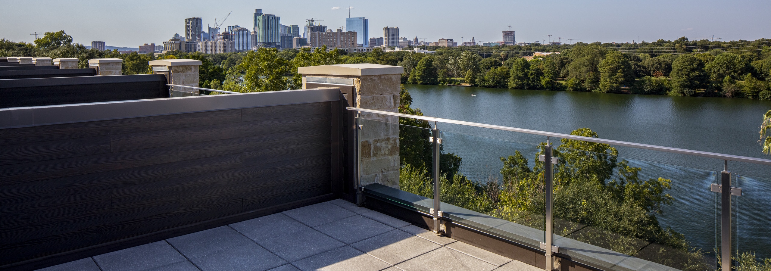 Daytime view of tree lined lake and downtown Austin skyline from 4th floor deck of AMLI South Shore lakefront apartment home