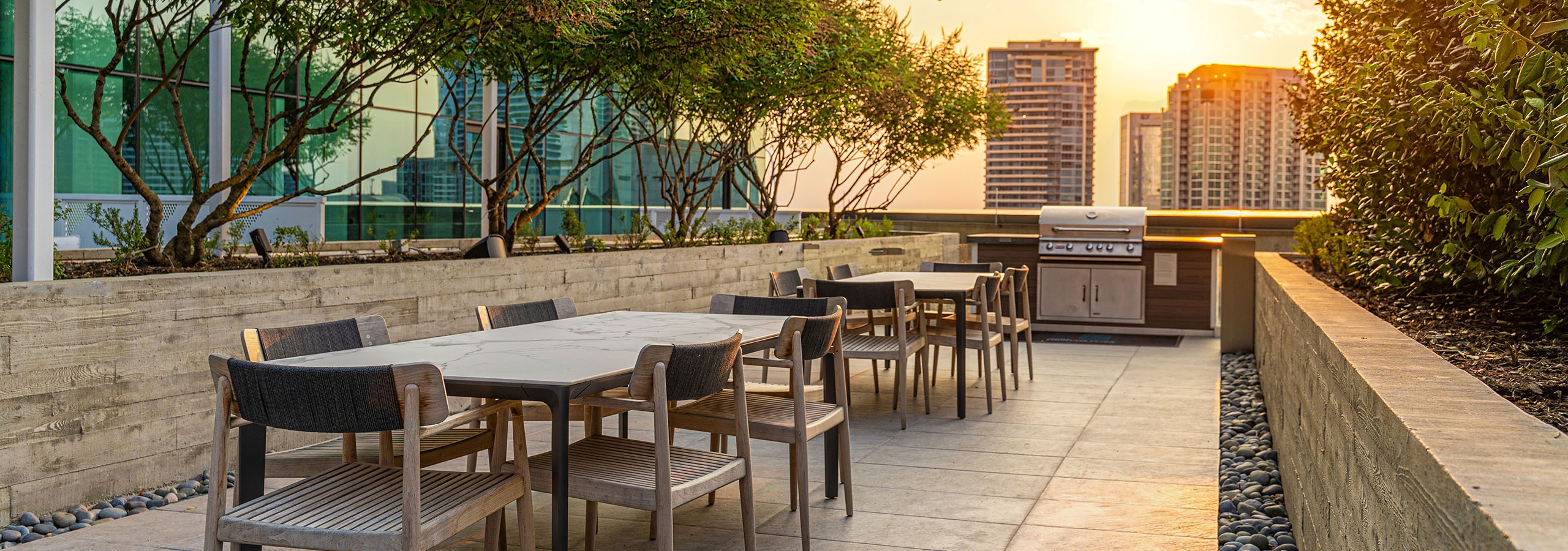 AMLI Fountain Place outdoor dining area with two white marble top tables with chairs near grill under hanging lights
