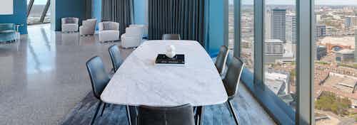AMLI Fountain Place sky lounge with large white table with 6 chairs next to wall of windows with 4 white chairs in rear