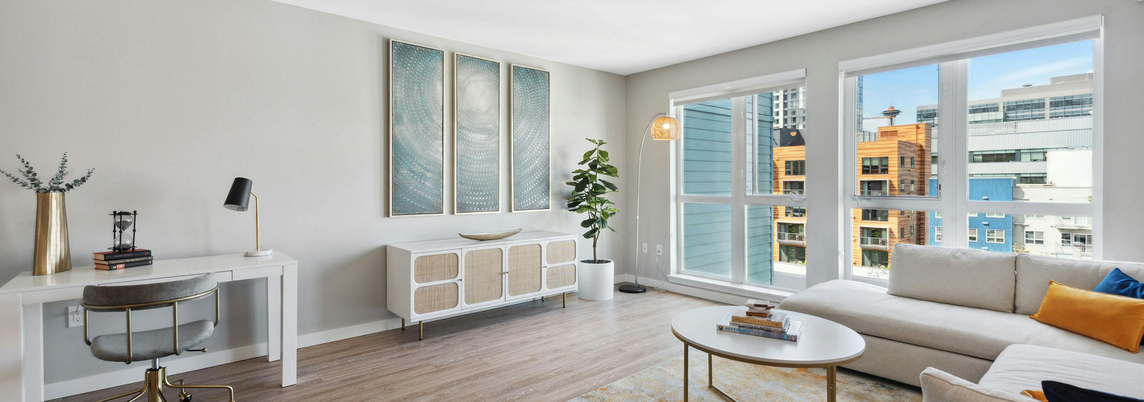 AMLI 535 living room with view of city and desk and sideboard with artwork and couch and multi color carpet with coffee table