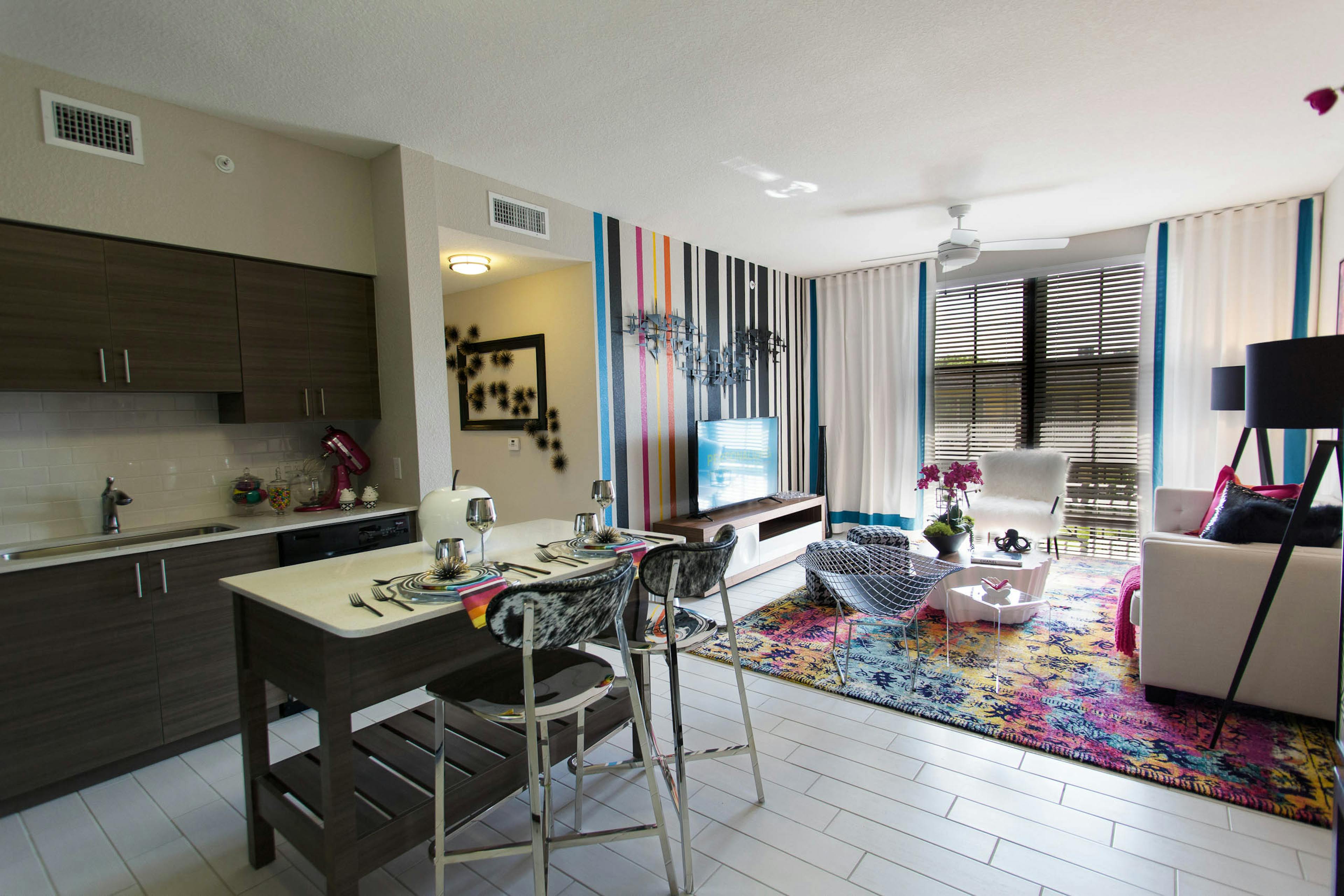 Interior of an AMLI Dadeland apartment living area with white sofa, modern colorful artwork and kitchen island with stools