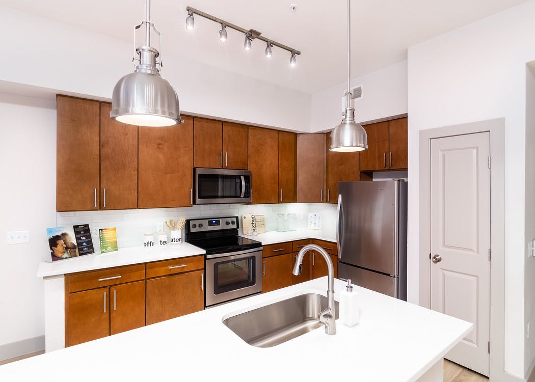 Interior view of a renovated kitchen island at AMLI Park Avenue apartments with white counter tops and many kitchen cabinets