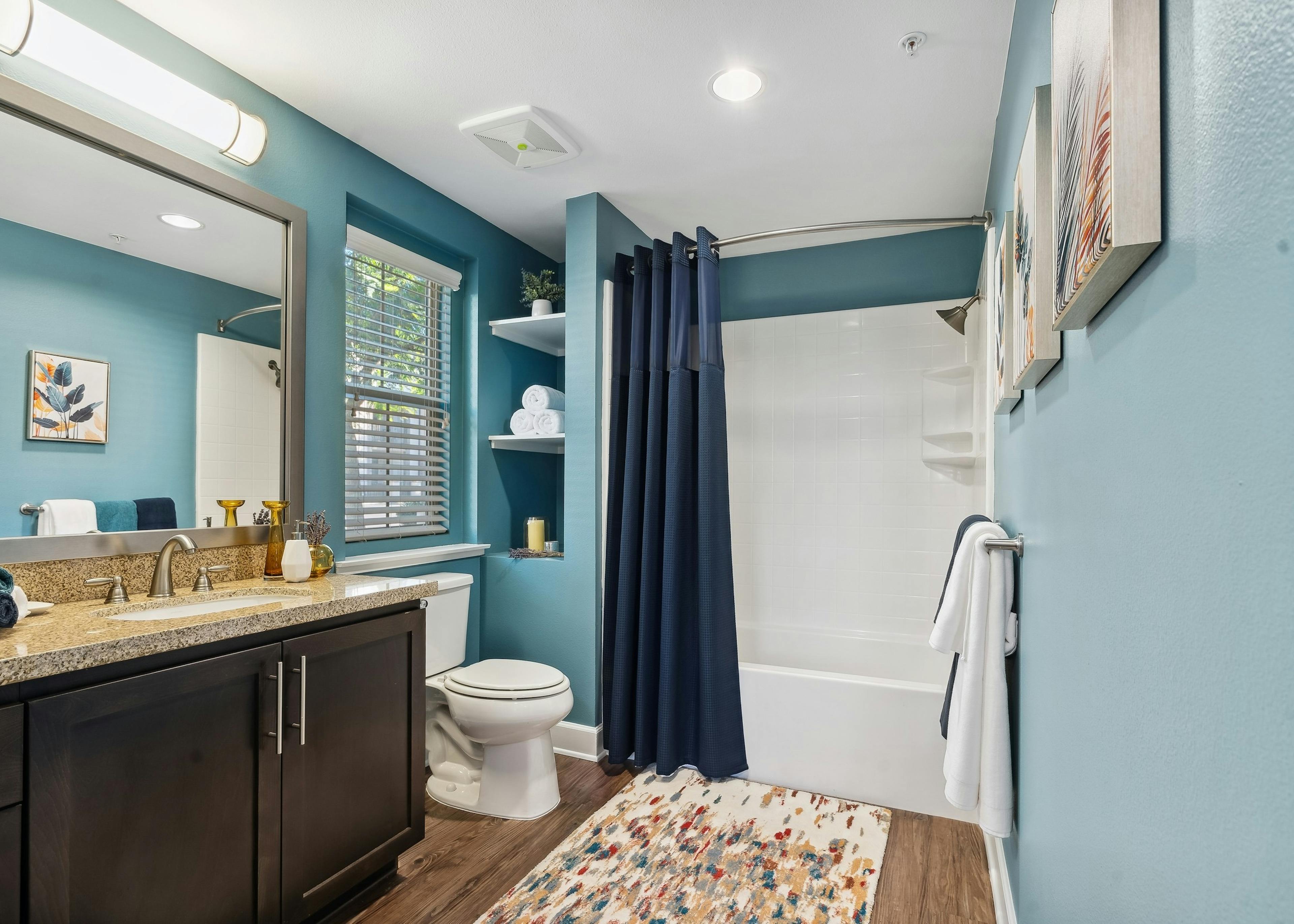Interior view of bathroom at AMLI Spanish Hills apartments with dark brown wood vanity and granite countertop and blue walls