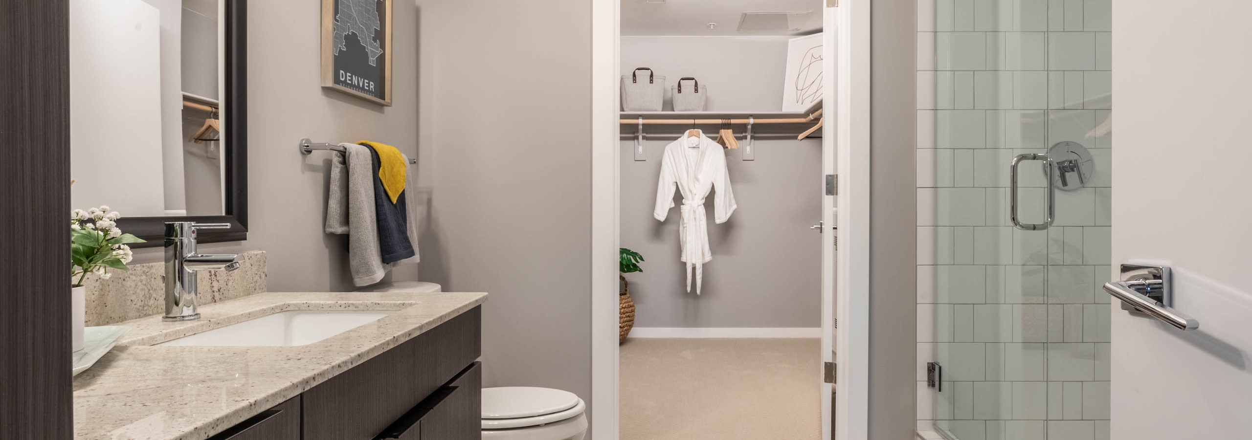 Close up view of modern vanity in an AMLI at Uptown apartment bathroom with view of spacious walk in closet in background