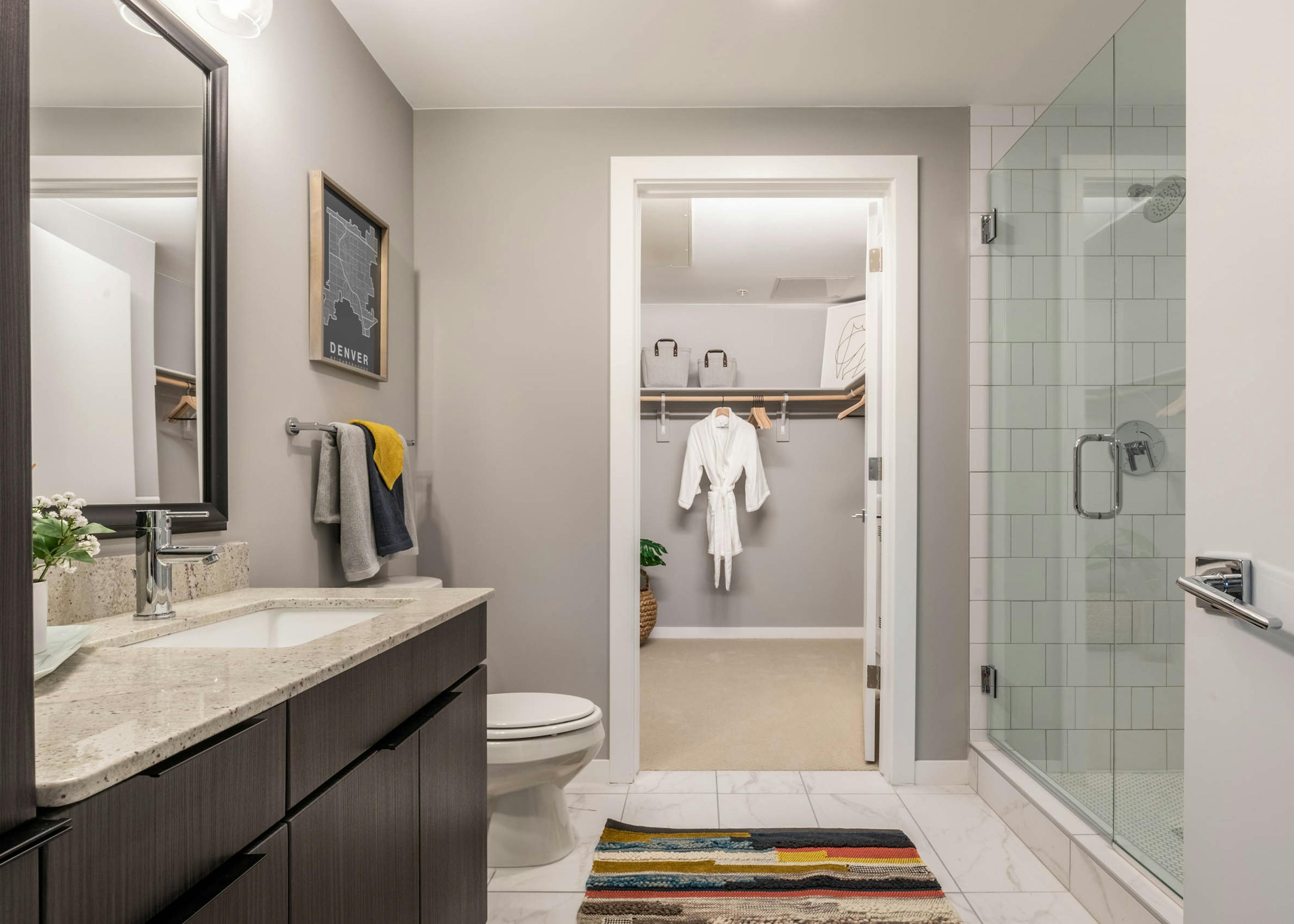 Close up view of modern vanity in an AMLI at Uptown apartment bathroom with view of spacious walk in closet in background 