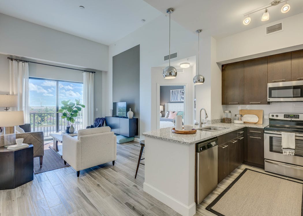 An apartment living room at AMLI Joya with cool neutral colors, a couch and coffee table and kitchen island with stools