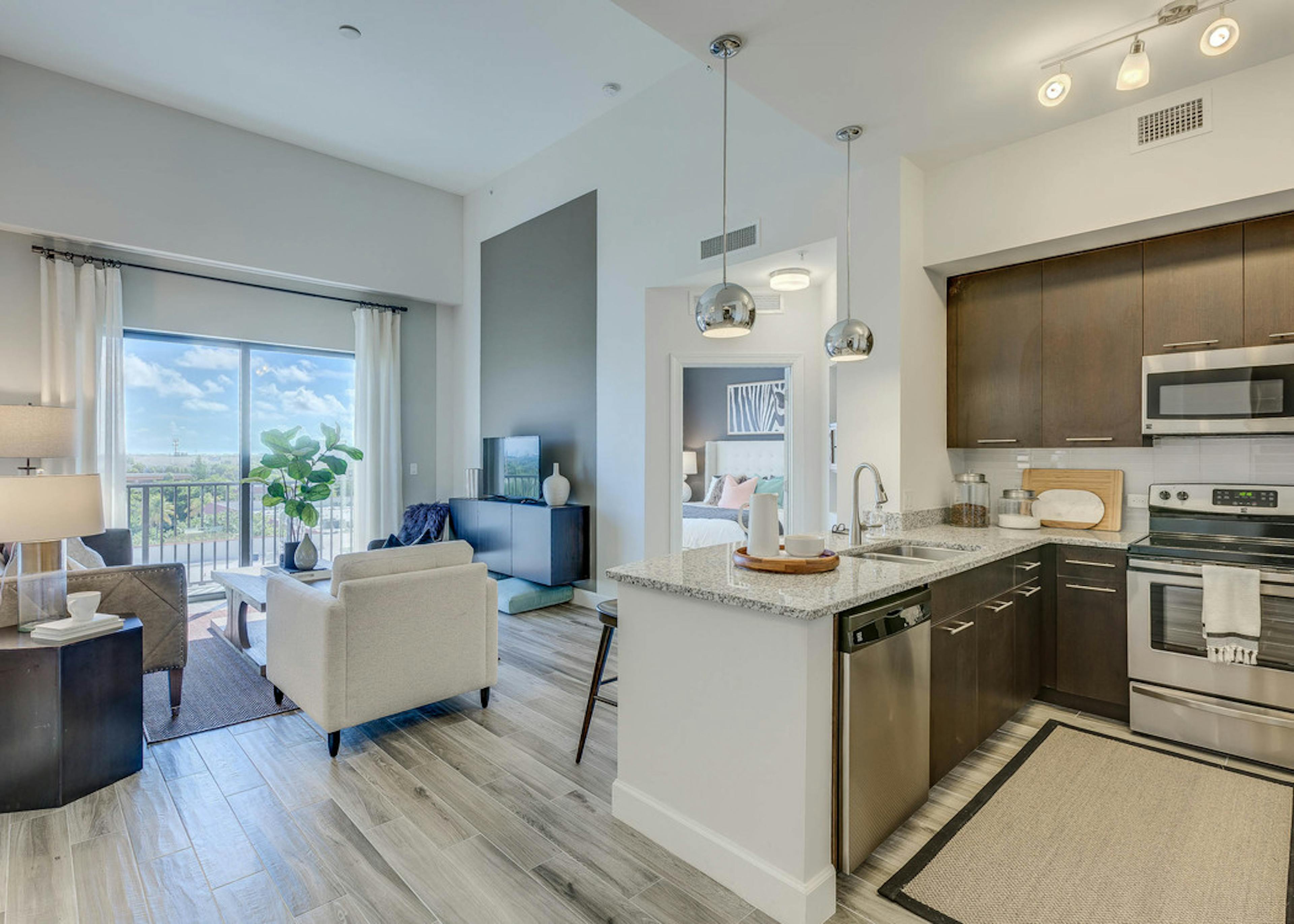  An apartment living room at AMLI Joya with cool neutral colors, a couch and coffee table and kitchen island with stools