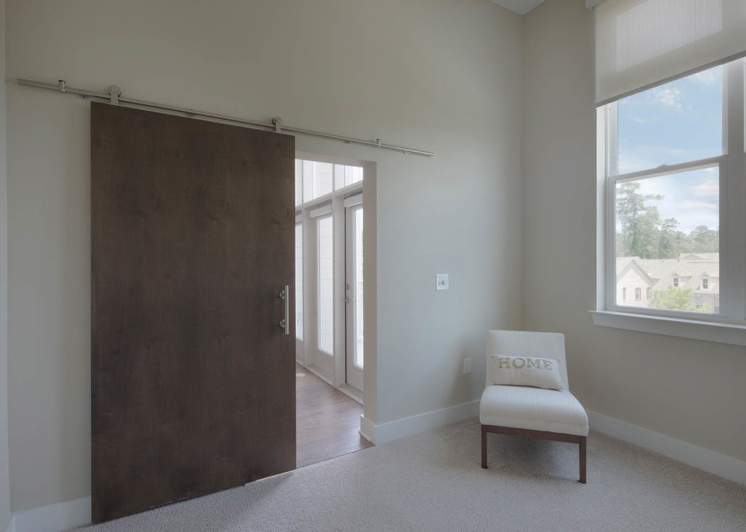 Interior view of a walk in closet at AMLI Buckhead with wooden hangers and white shelving with beige colored walls