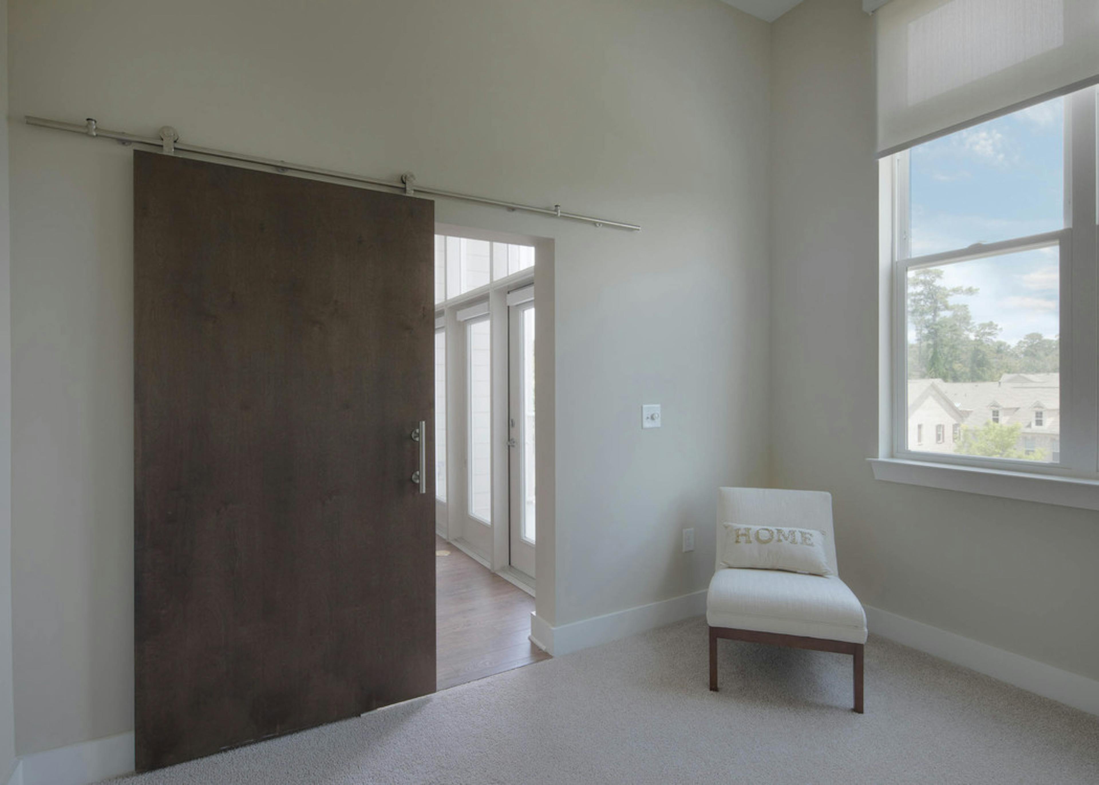 Interior view of a walk in closet at AMLI Buckhead with wooden hangers and white shelving with beige colored walls