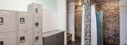 Interior of boat house bathroom showers with pebble tile accent walls and storage lockers at AMLI Marina Del Rey apartments