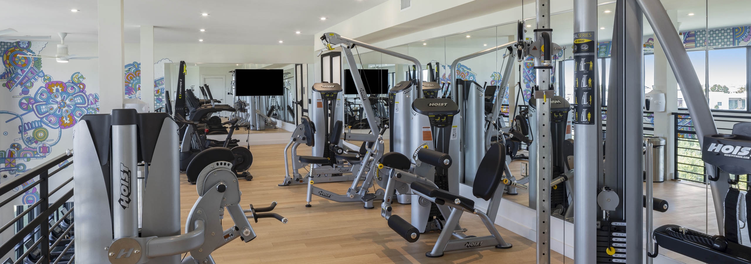 Fitness center with workout equipment and mirror wall with light wood floors and graphic wall design at AMLI Branch Park