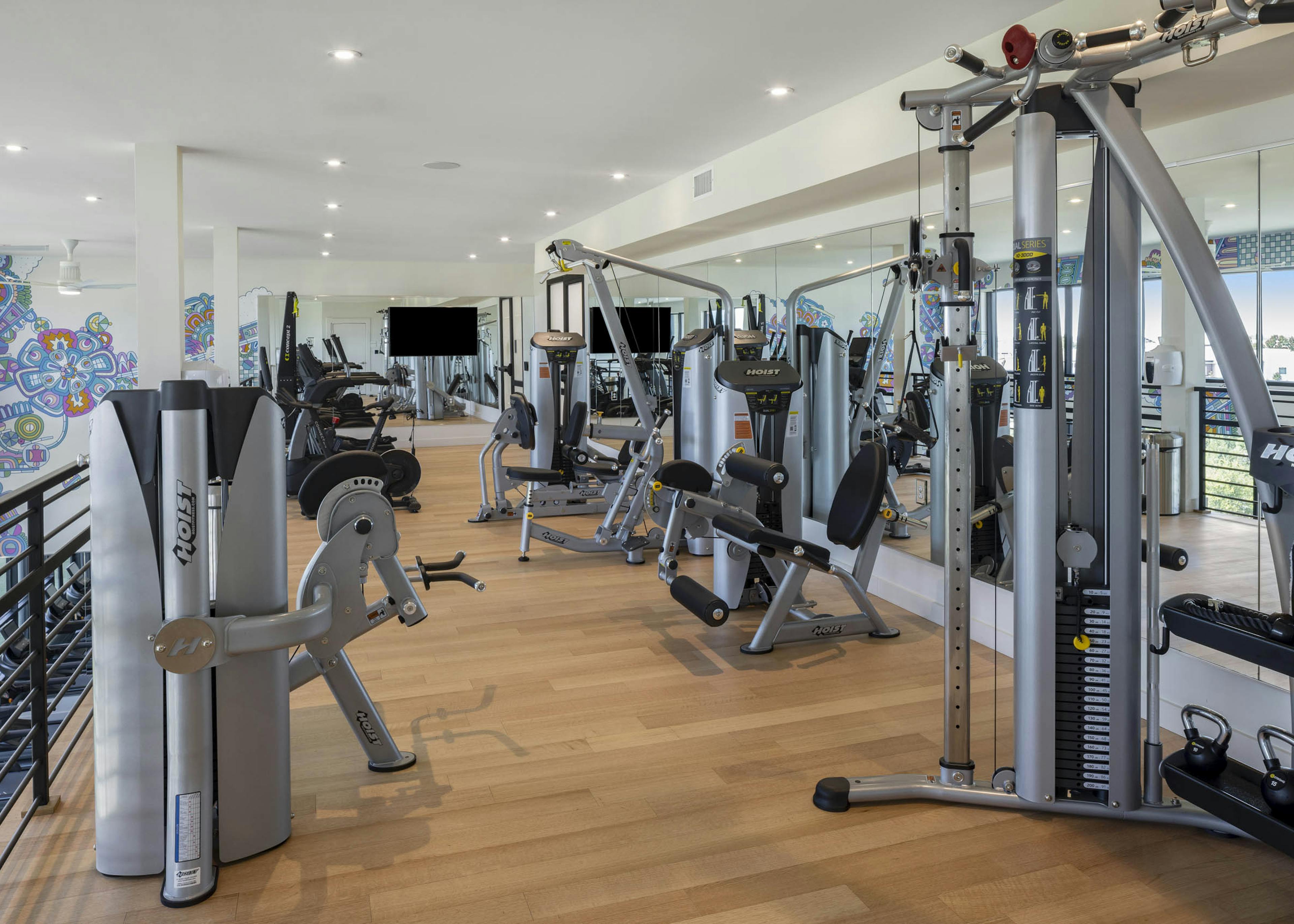 Fitness center with workout equipment and mirror wall with light wood floors and graphic wall design at AMLI Branch Park