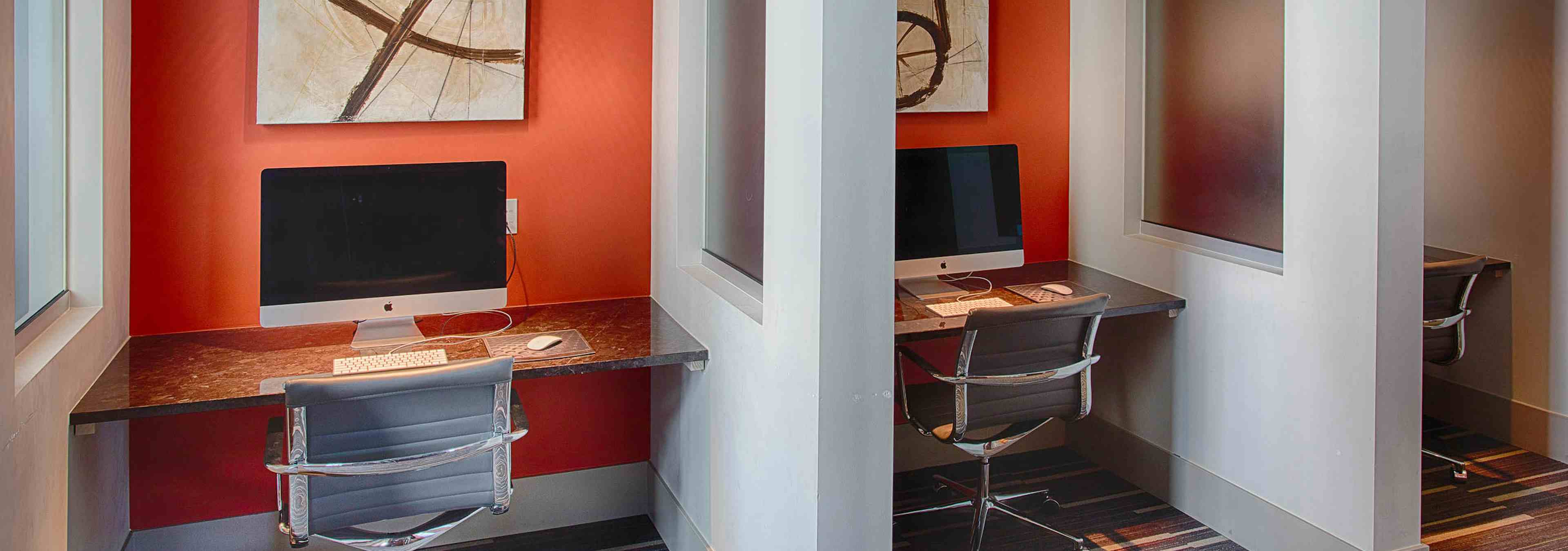 Business center at AMLI Denargo Market apartments with several desks and computers with rolling chairs and wall artwork