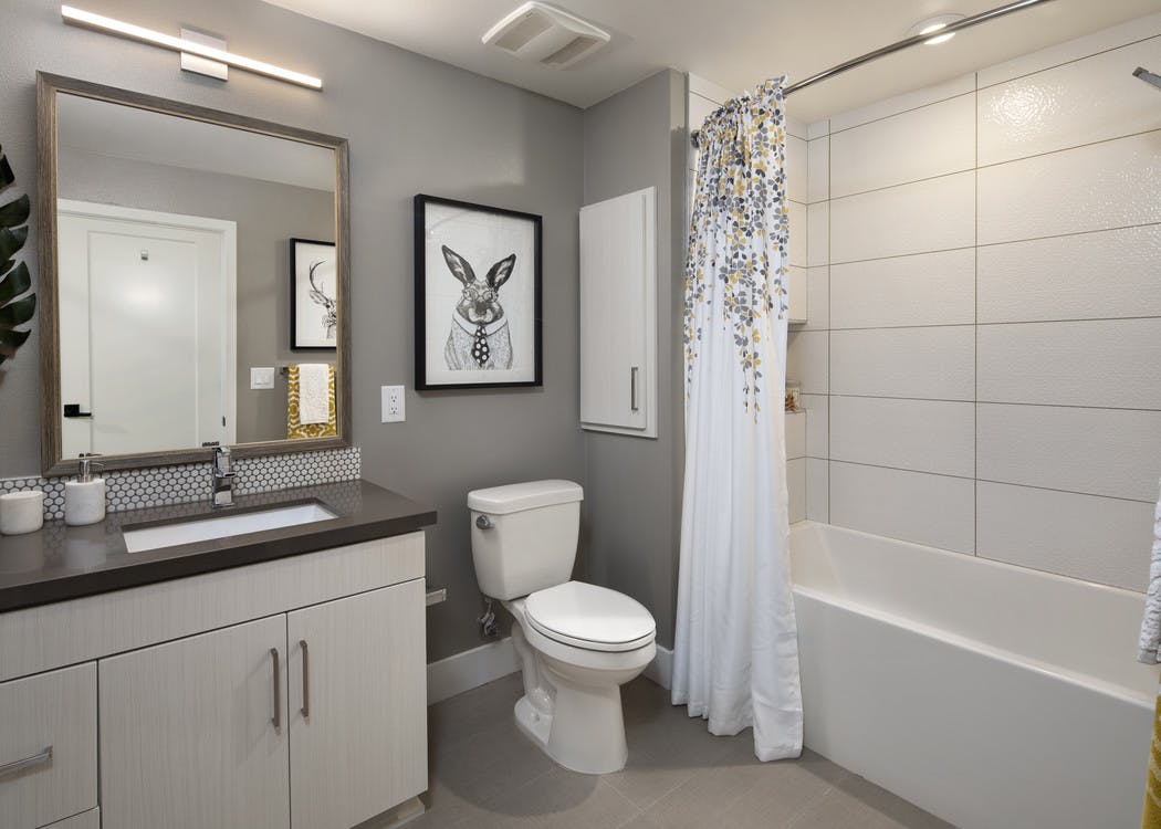 Interior of AMLI Marina Del Rey apartment bathroom with grey quartz countertop and soaking tub, tile surround and soap niche