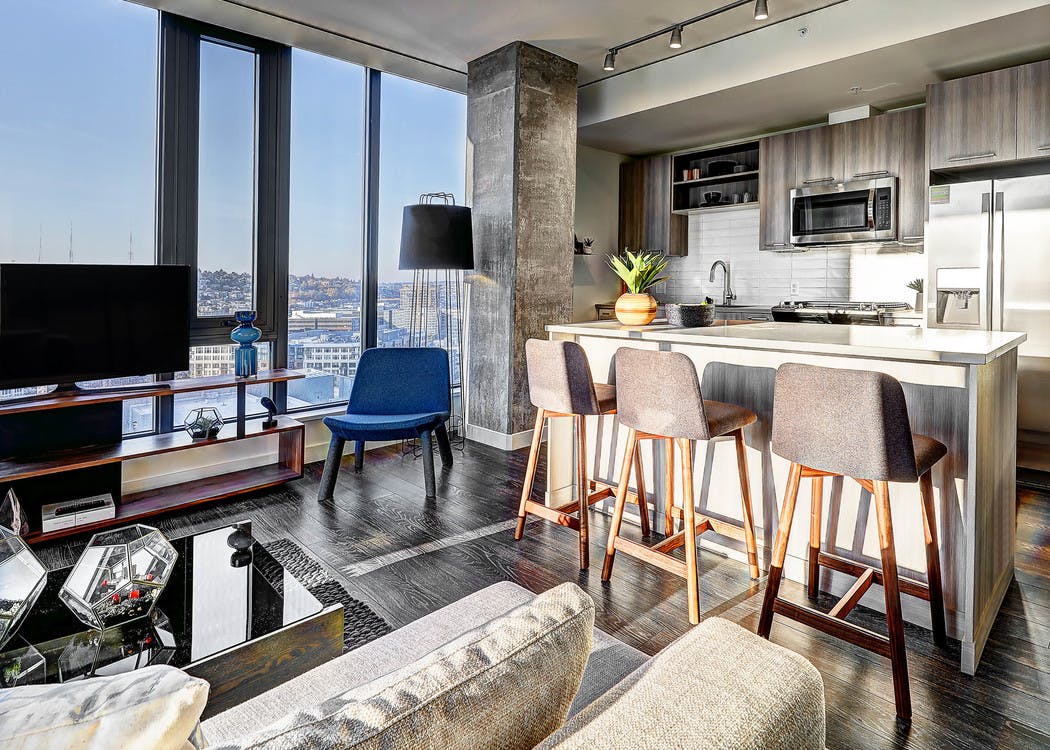 Interior view of apartment of AMLI Arc of kitchen with island with white quartz counter tops and living room and large window