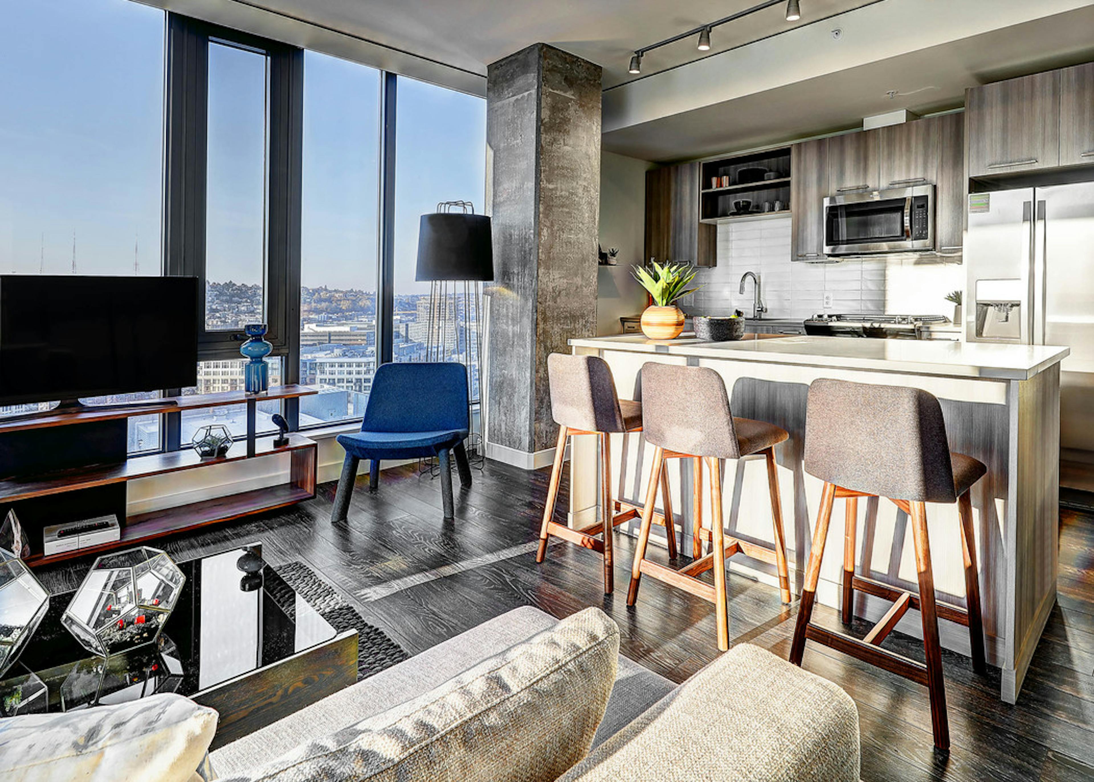Interior view of apartment of AMLI Arc of kitchen with island with white quartz counter tops and living room and large window