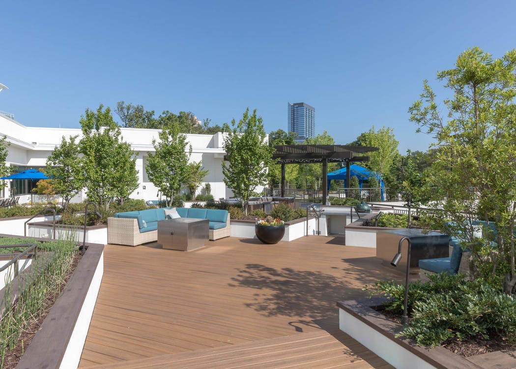 AMLI 3464 rooftop sundeck with scattered trees and blue outdoor couch with wooden pergola and blue canopy in the background