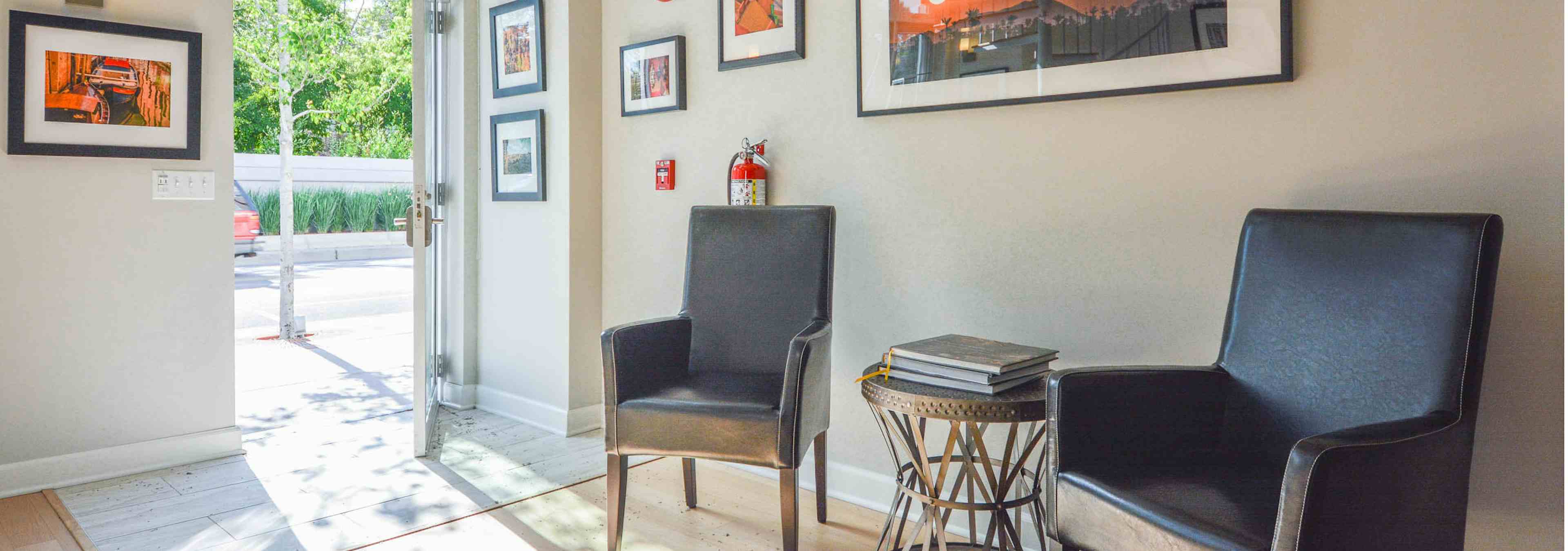 AMLI Evanston live/work interior with black leather chairs lined against creme colored walls with orange wall art