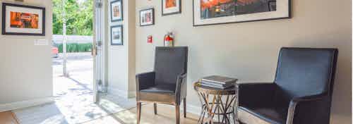 AMLI Evanston live/work interior with black leather chairs lined against creme colored walls with orange wall art