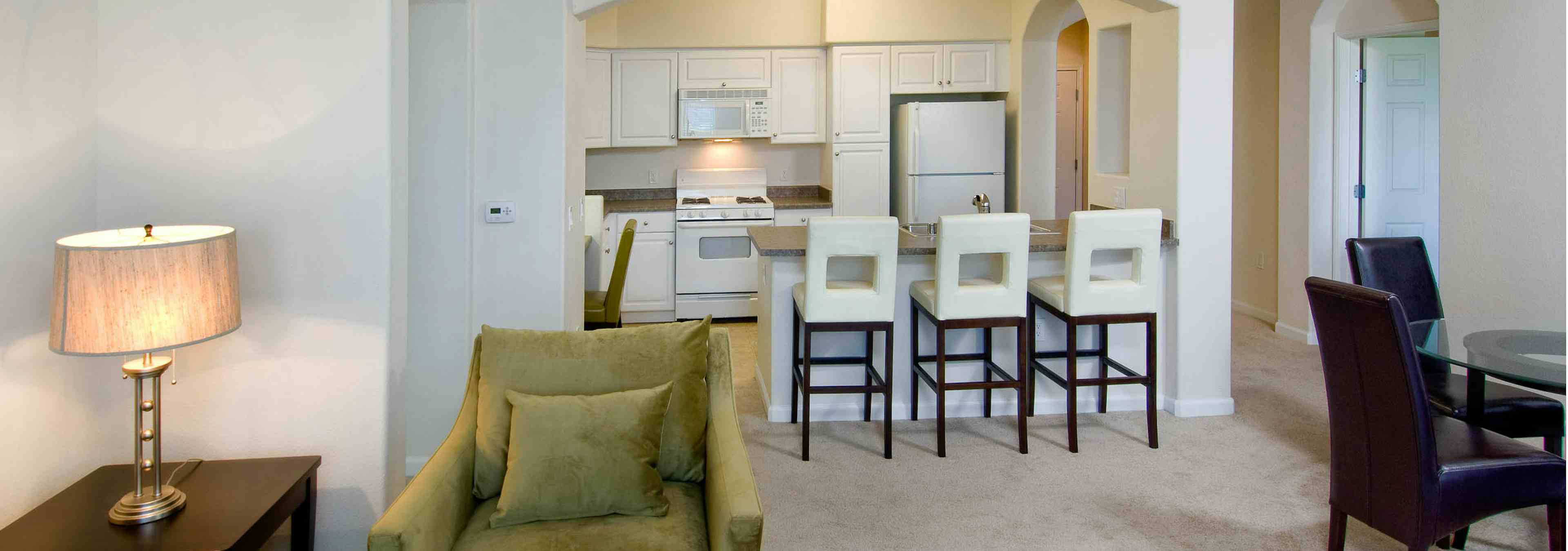 Interior view of AMLI Warner Center furnished apartment living room and kitchen with white cabinetry and white appliances