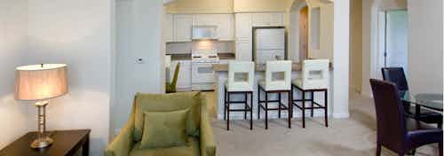 Interior view of AMLI Warner Center furnished apartment living room and kitchen with white cabinetry and white appliances