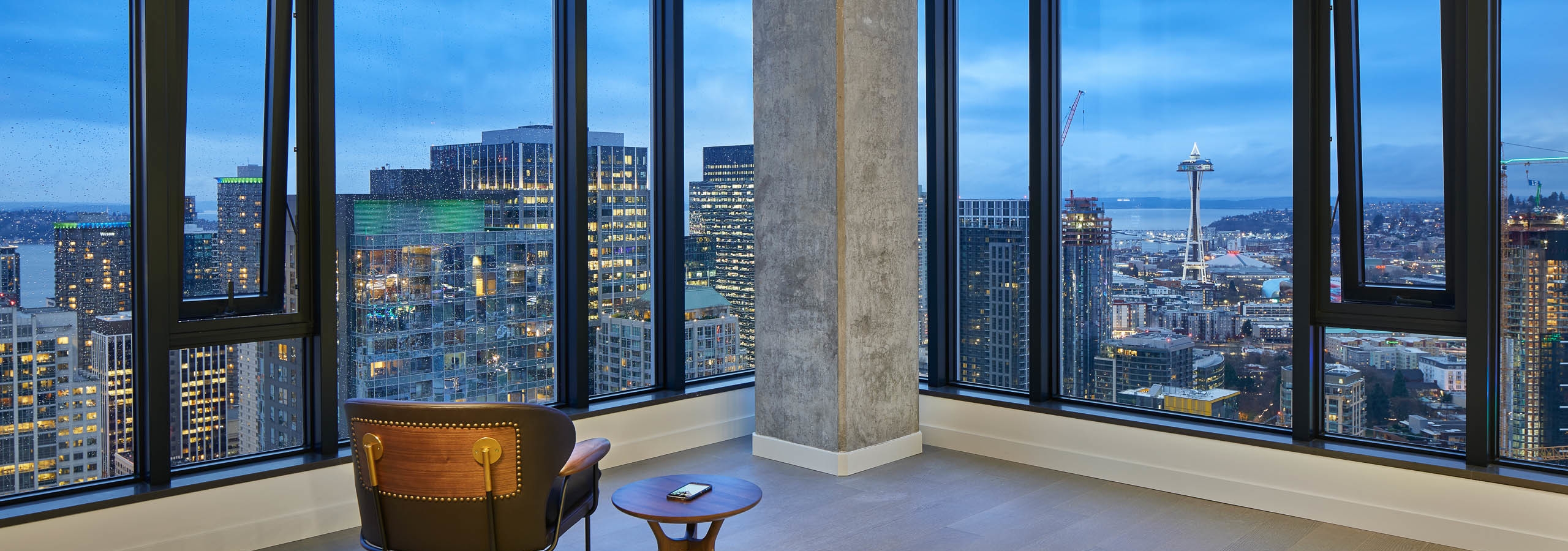 Interior view of apartment of AMLI Arc penthouse living room with floor to ceiling windows and view of Downtown Seattle