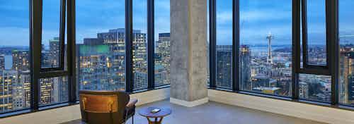 Interior view of apartment of AMLI Arc penthouse living room with floor to ceiling windows and view of Downtown Seattle