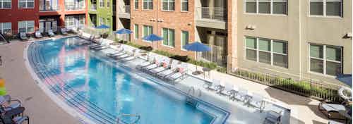 Exterior daytime view of pool area at AMLI at Mueller facing multicolored building facade with umbrellas and lounge chairs