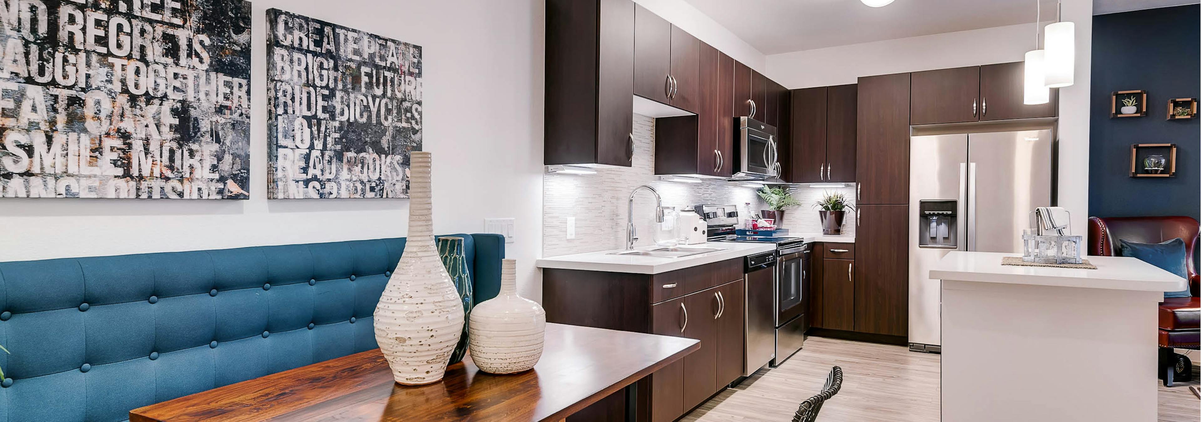 A kitchen and dining room at AMLI Cherry Creek apartments with an island and a dining room table and artwork on the wall