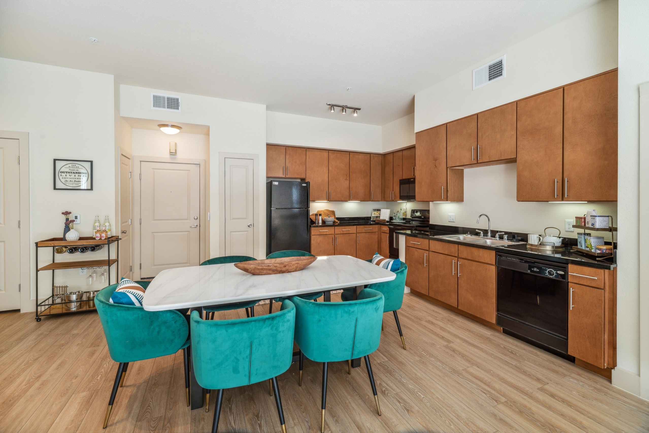 Kitchen and dining area at AMLI Park Avenue apartments with a long black countertop with wood cabinets and dining table