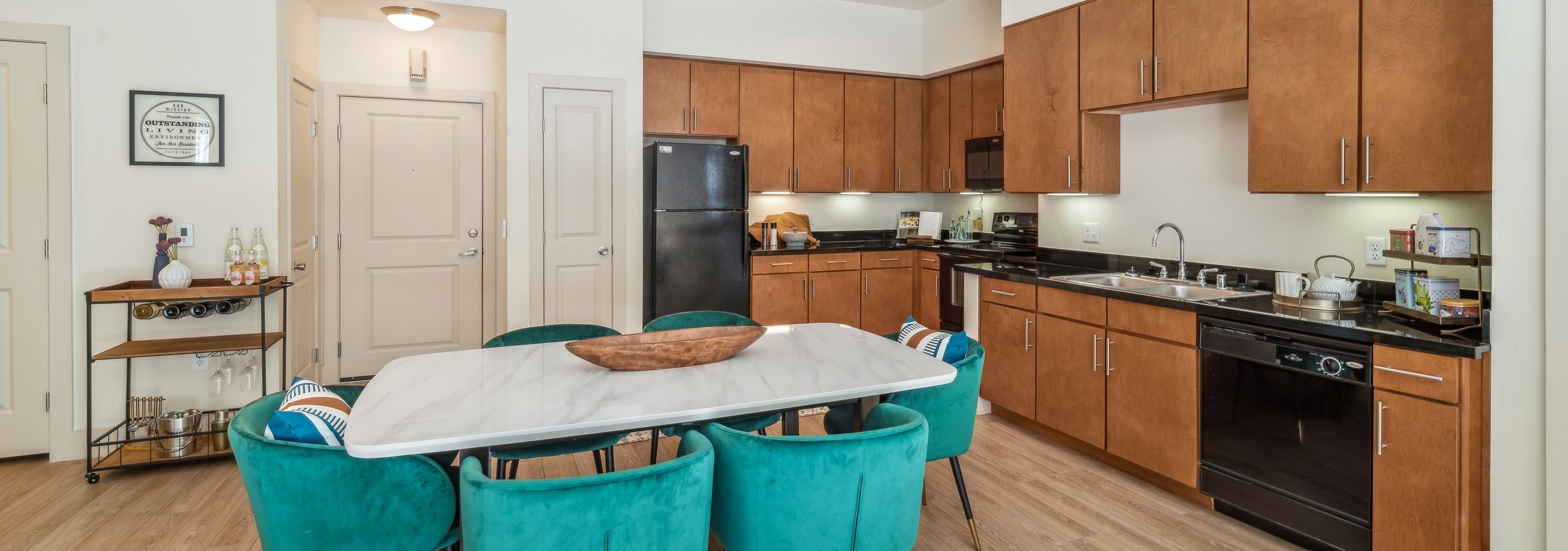 Kitchen and dining area at AMLI Park Avenue apartments with a long black countertop with wood cabinets and dining table