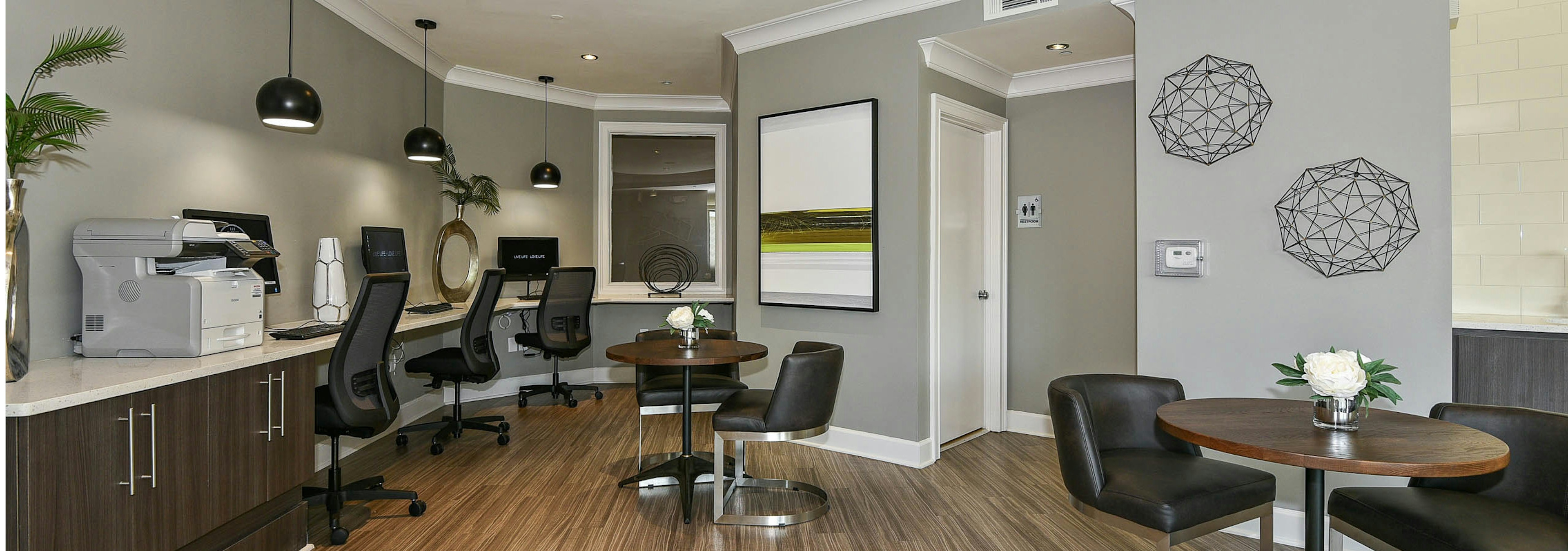 Interior view of AMLI Lindbergh apartment business center with three computer desktops and a printer with tables and chairs