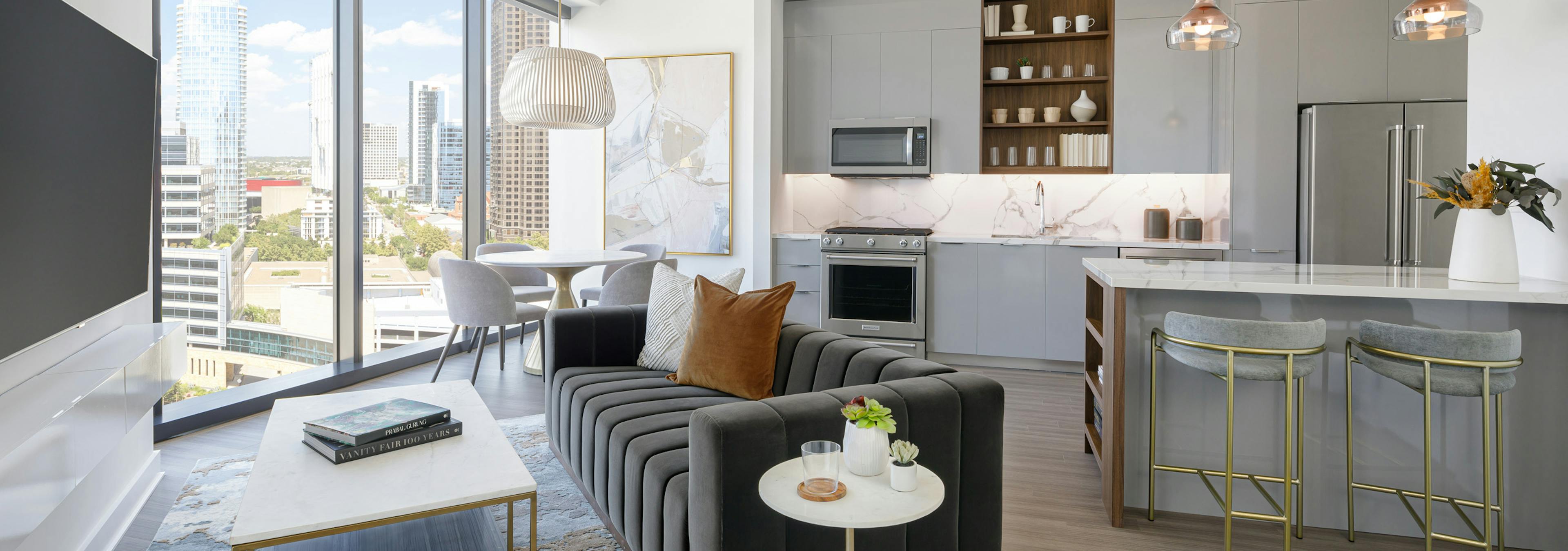 AMLI Fountain Place apartment kitchen with grey cabinets and living area with couch and dining table in front of large window