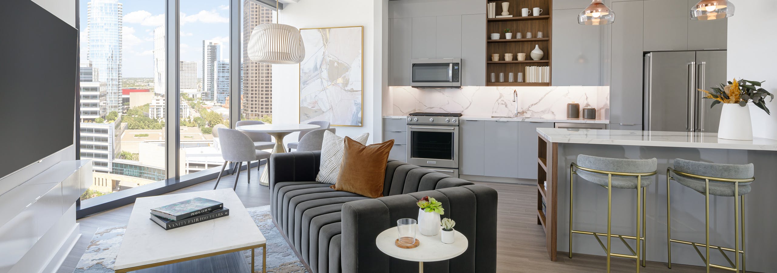 AMLI Fountain Place apartment kitchen with grey cabinets and living area with couch and dining table in front of large window