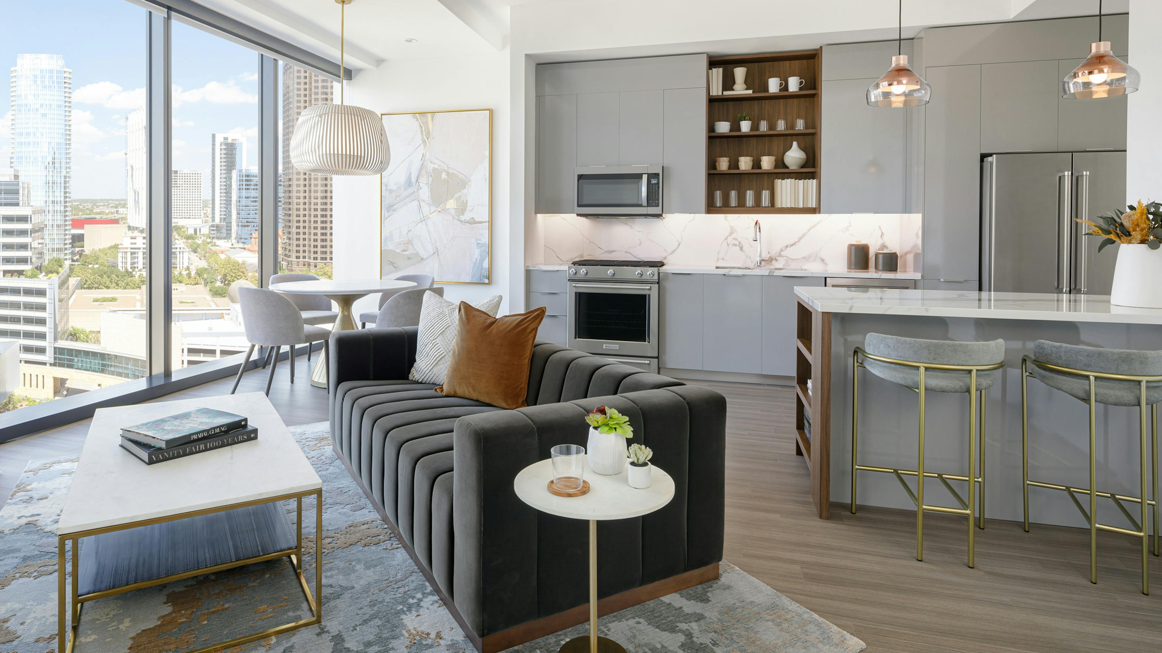 AMLI Fountain Place apartment kitchen with grey cabinets and living area with couch and dining table in front of large window