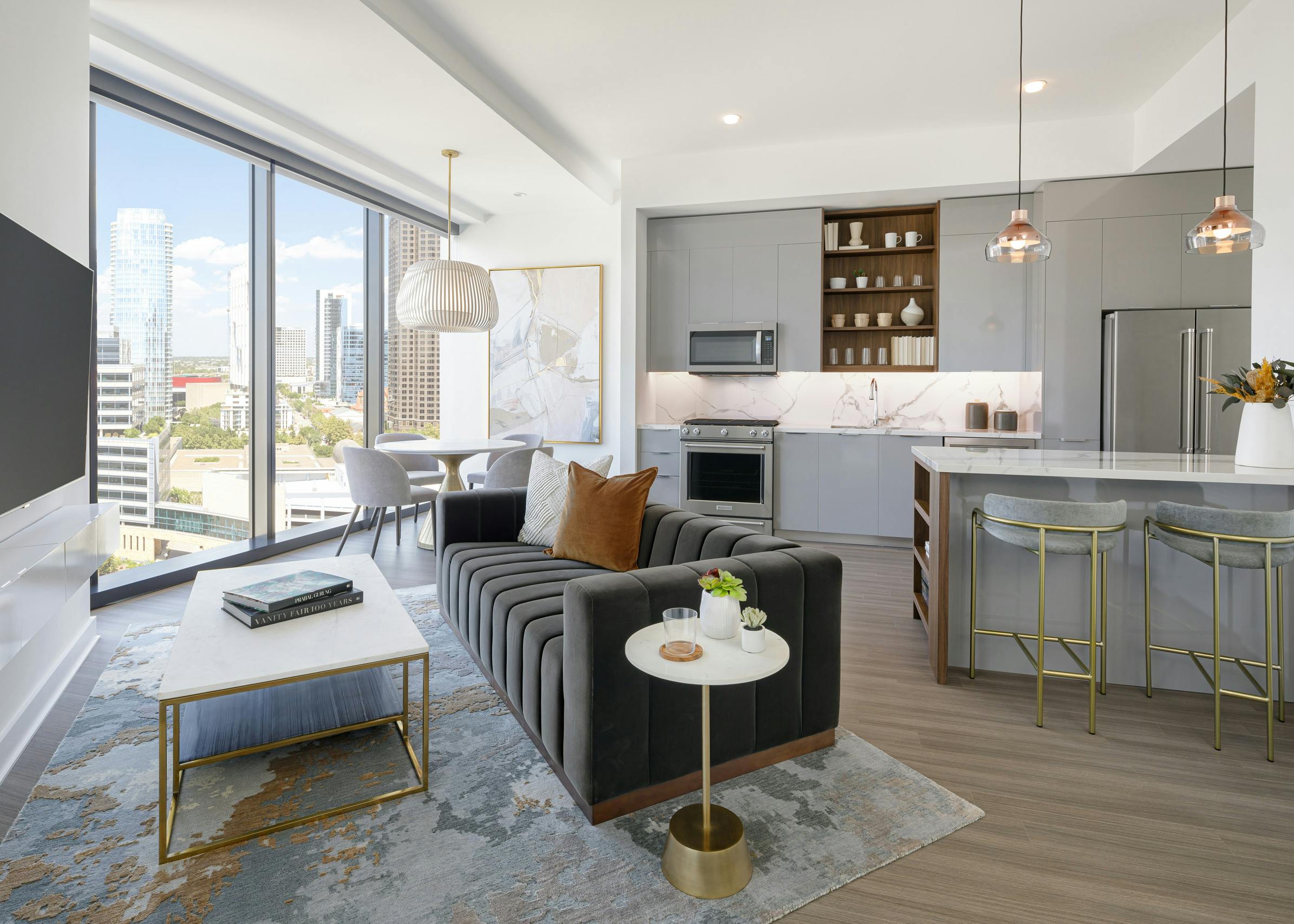 AMLI Fountain Place apartment kitchen with grey cabinets and living area with couch and dining table in front of large window