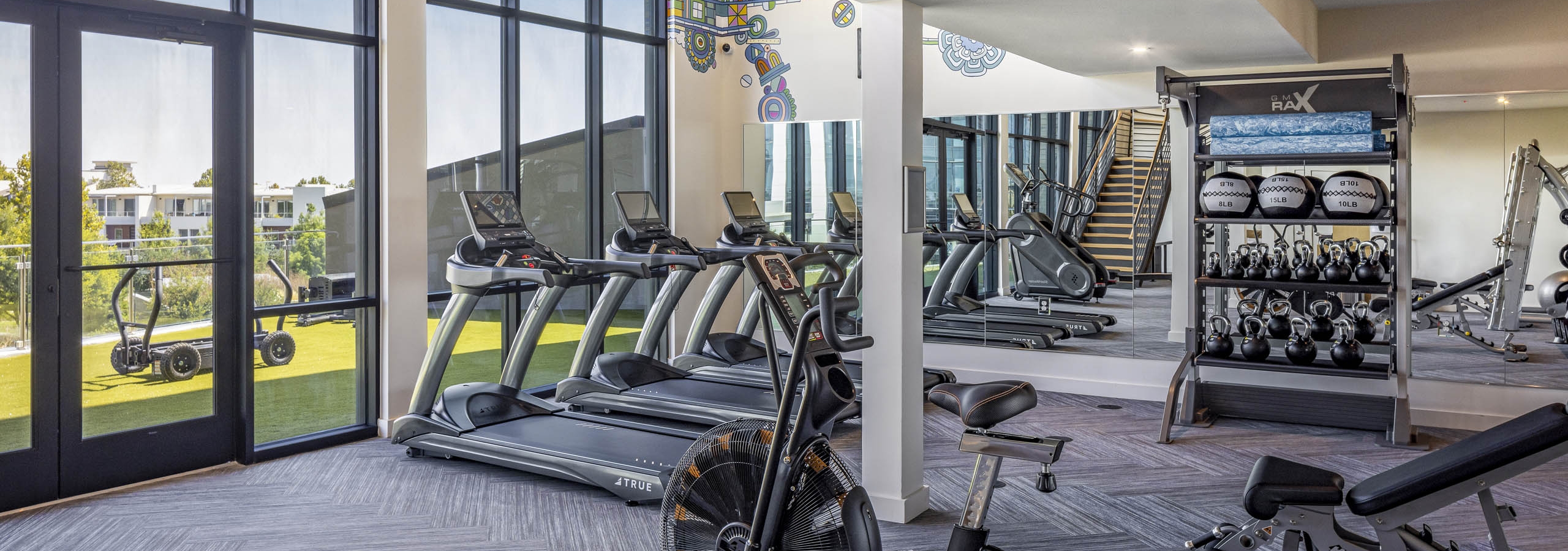 AMLI Branch Park fitness center with weathered grey floor and treadmills and mirrored wall facing outdoor fitness deck