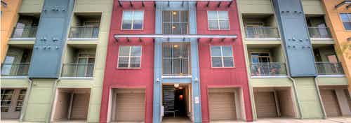 A daytime exterior view at AMLI Arista apartments showcasing several multi colored balconies and garages with a staircase