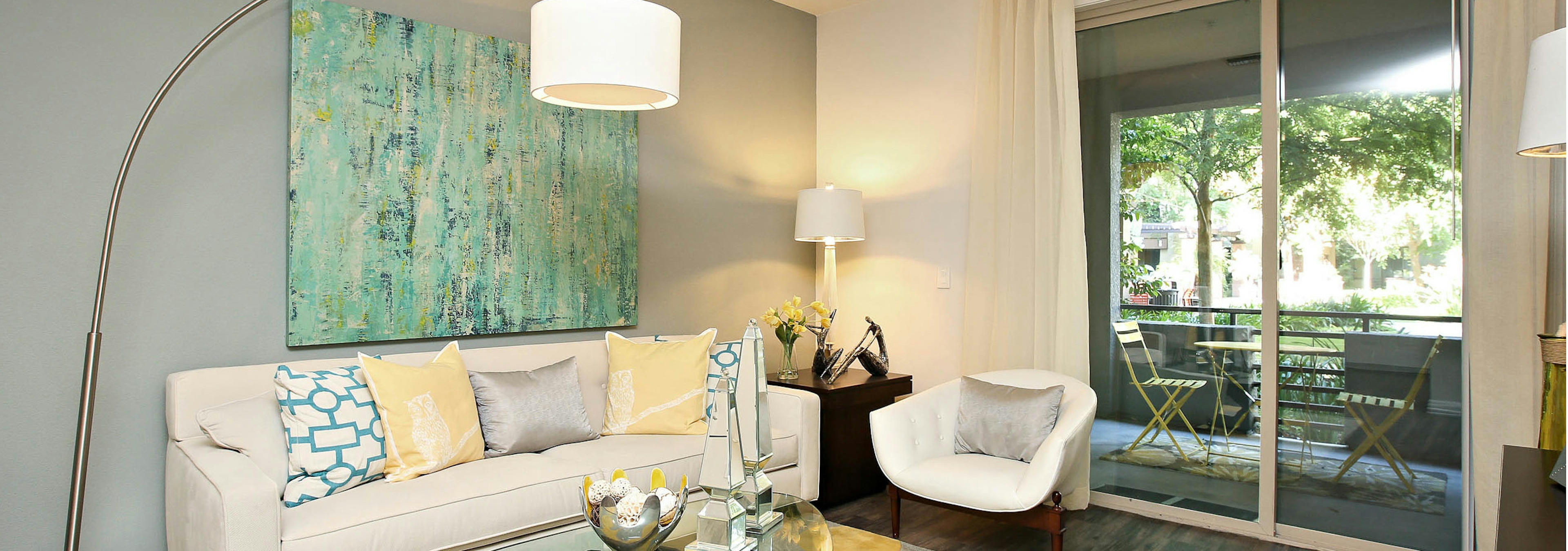 Interior view of AMLI Warner Center apartment living room with white couch and chair on area rug overlooking private patio 