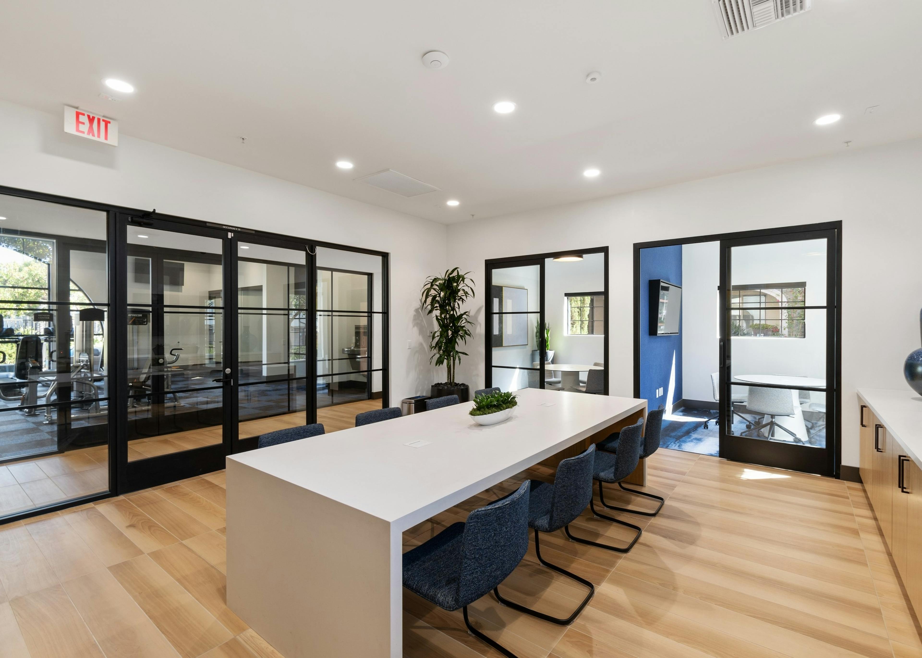 WiFi lounge at AMLI Spanish Hills apartments with alcove offices and long white table with 6 blue chairs and glass doors