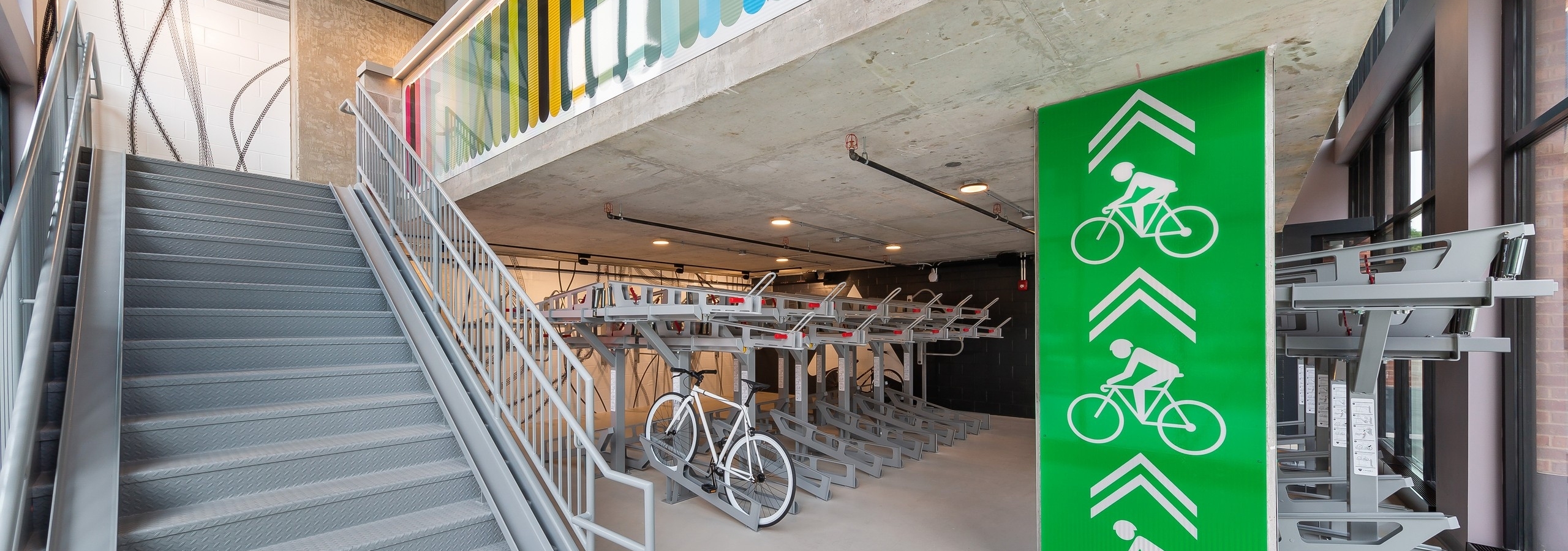 Close up of industrial bike storage room at AMLI 808 featuring grey bike racks with wide stairs leading to an upper level