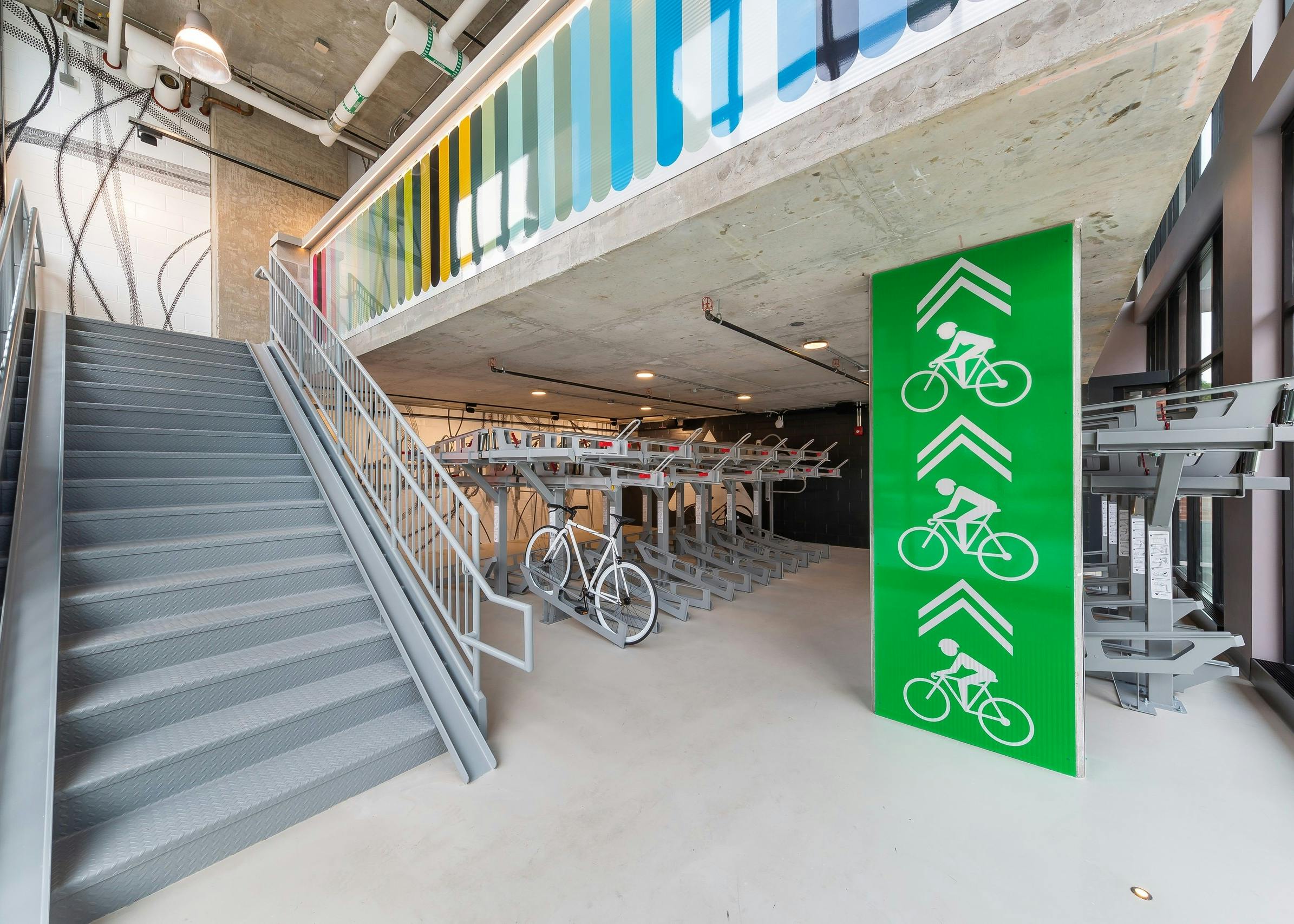 Close up of industrial bike storage room at AMLI 808 featuring grey bike racks with wide stairs leading to an upper level
