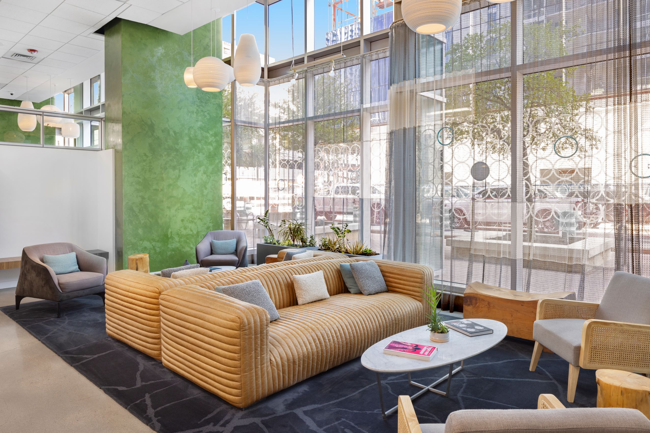 AMLI on 2nd lobby with floor to ceiling windows and green wall with gold sofas and a few chairs around coffee table